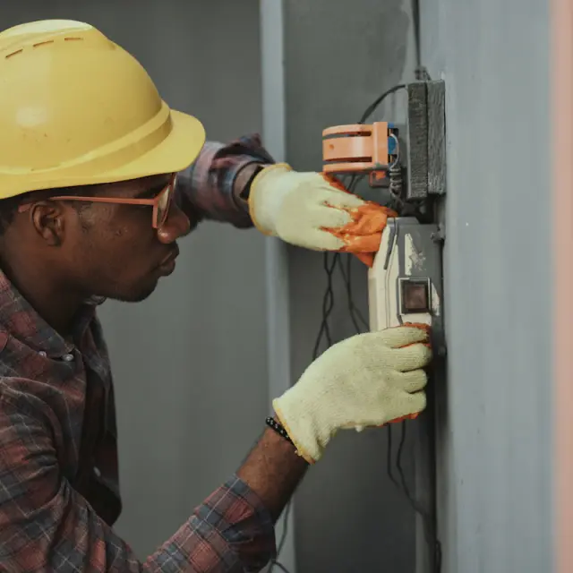 Electrician in a hard hat wiring an electrical box