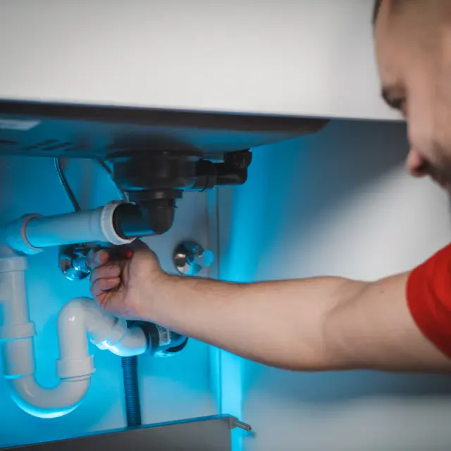 Plumber repairing the drain pipes under a sink